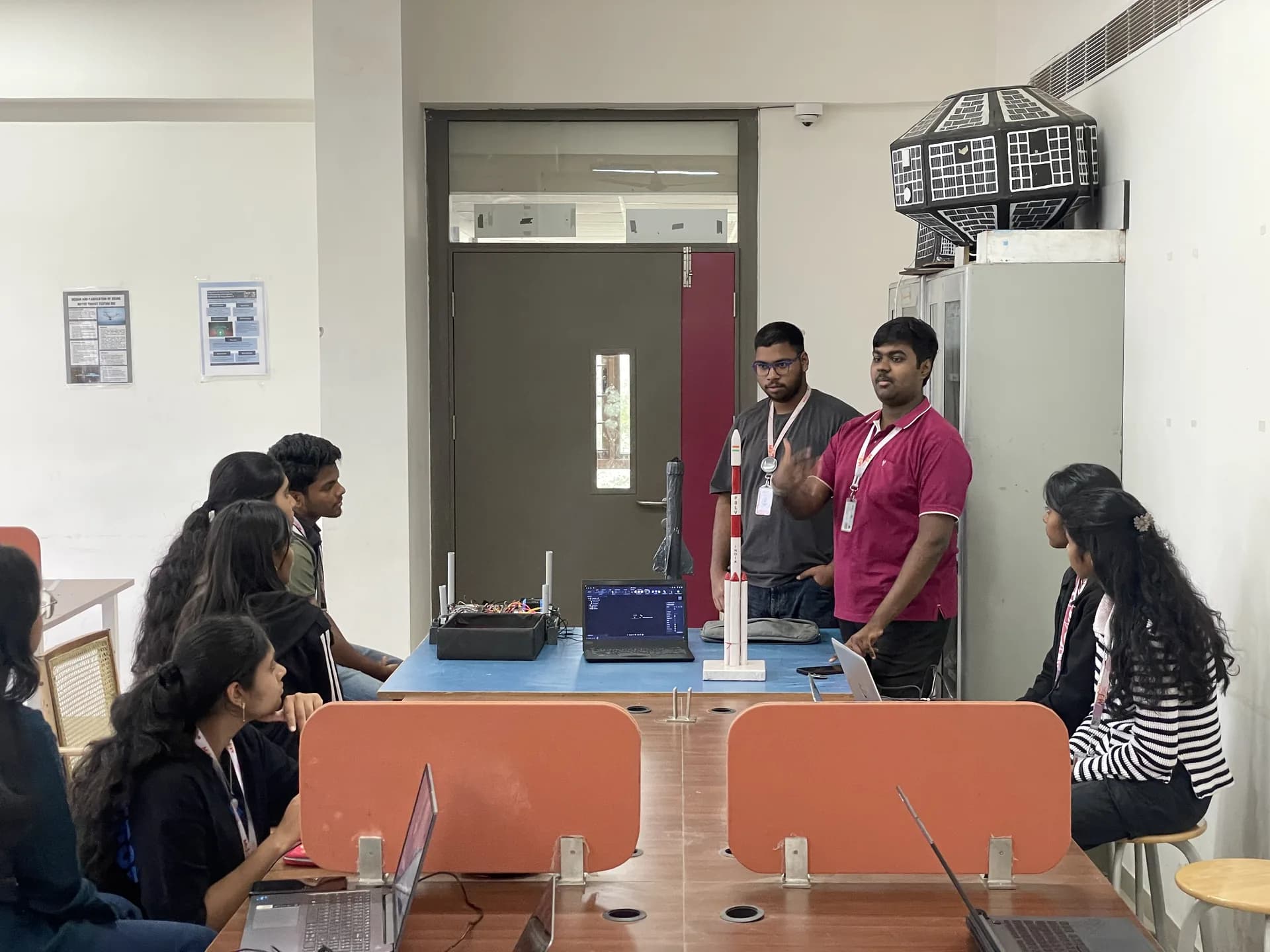 Club members presenting a model rocket and its electronics