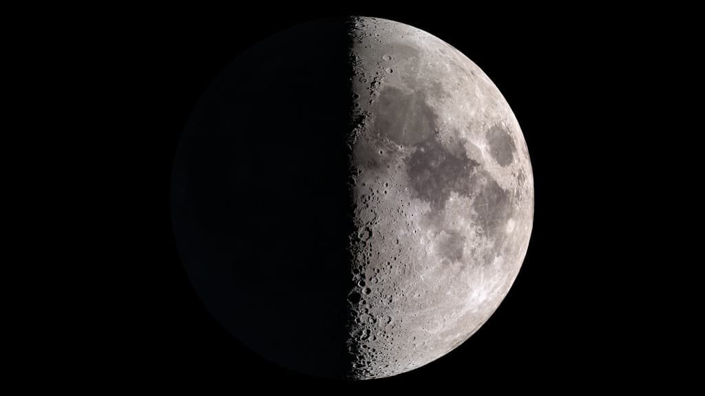 The Moon half illuminated against black space